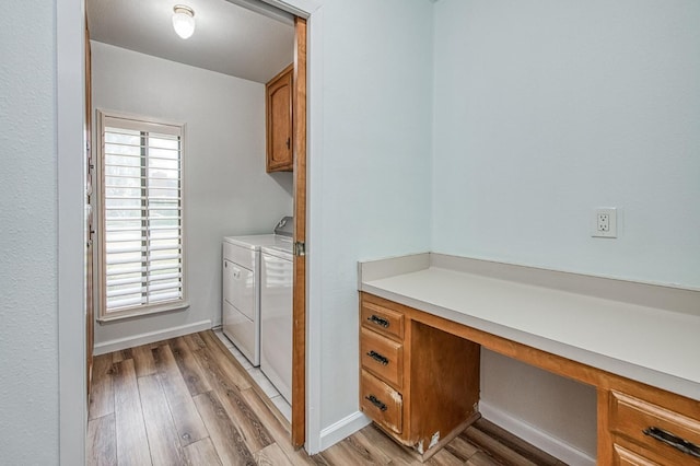 washroom with cabinet space, baseboards, light wood finished floors, and washing machine and clothes dryer