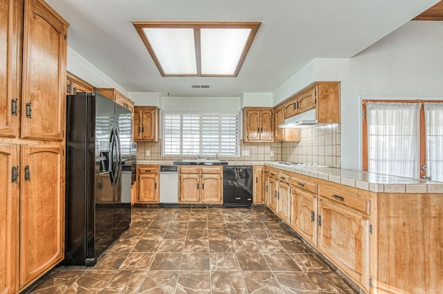 kitchen featuring visible vents, a sink, black appliances, under cabinet range hood, and backsplash