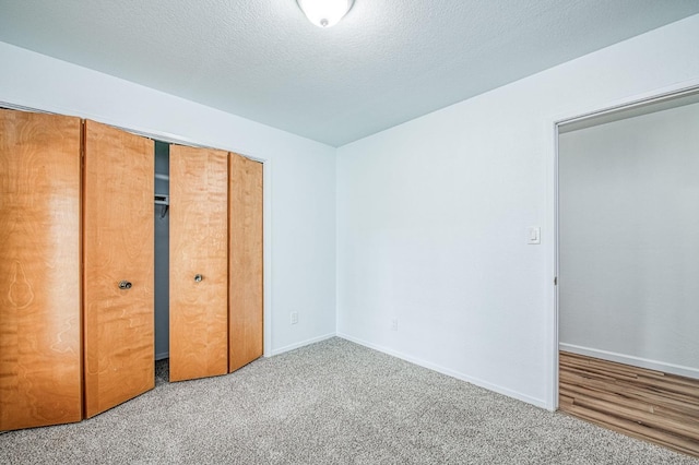 unfurnished bedroom featuring a closet, a textured ceiling, baseboards, and carpet