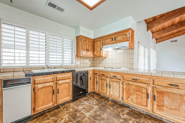 kitchen with under cabinet range hood, visible vents, black dishwasher, and a sink