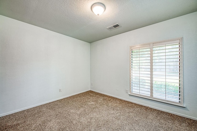 empty room featuring baseboards, visible vents, carpet floors, and a textured ceiling