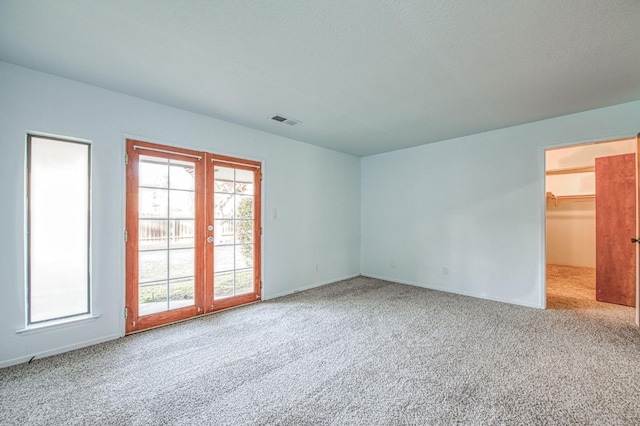 carpeted empty room featuring visible vents, french doors, and baseboards