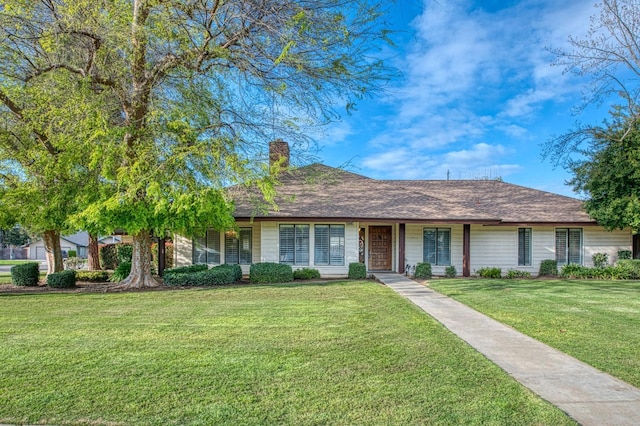 single story home with a shingled roof, a front lawn, and a chimney