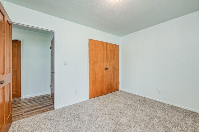 unfurnished bedroom featuring a closet, baseboards, a textured ceiling, and carpet flooring