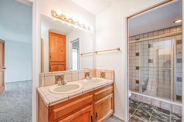 full bath featuring a sink, toilet, double vanity, and a shower stall