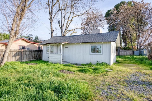 exterior space featuring fence, a lawn, roof with shingles, and a chimney