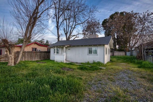 rear view of property with a chimney, a fenced backyard, and roof with shingles