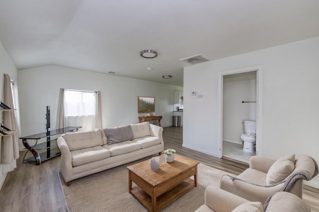 living area with lofted ceiling, light wood-style flooring, baseboards, and visible vents