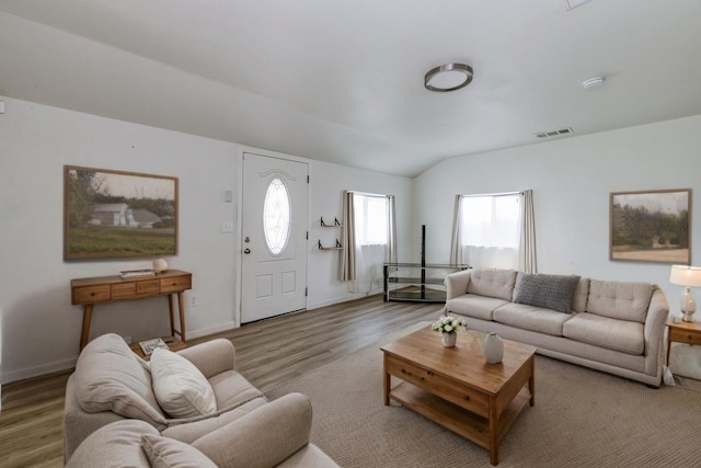 living area with visible vents, lofted ceiling, baseboards, and wood finished floors