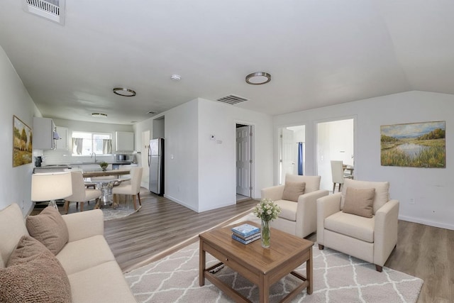 living area with visible vents, baseboards, and light wood-style flooring