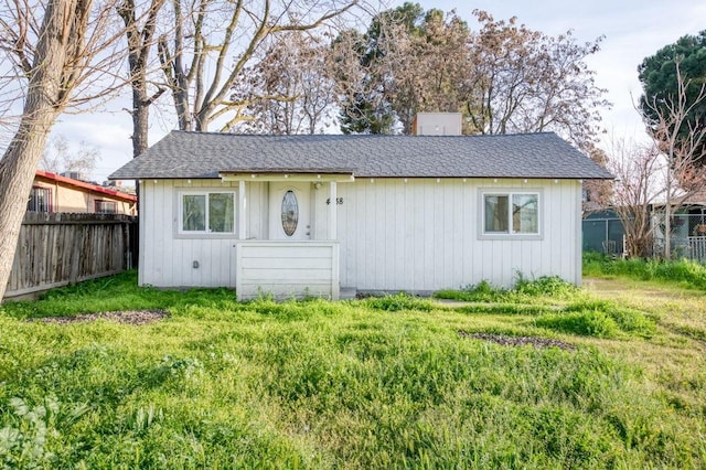 bungalow with a shingled roof, fence, and a chimney