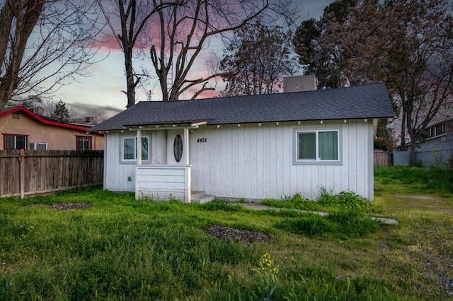 bungalow-style house featuring a front yard, fence, and roof with shingles