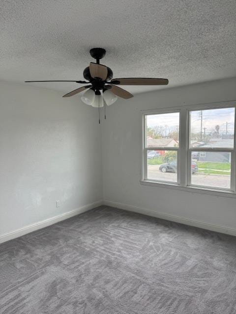 carpeted spare room with a wealth of natural light, a ceiling fan, and baseboards