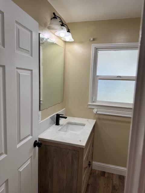 bathroom with vanity, wood finished floors, and baseboards