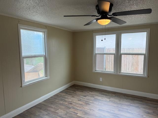 unfurnished room featuring baseboards, ornamental molding, wood finished floors, a textured ceiling, and a ceiling fan