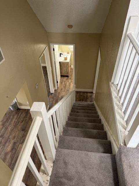 stairs featuring wood finished floors and a textured ceiling