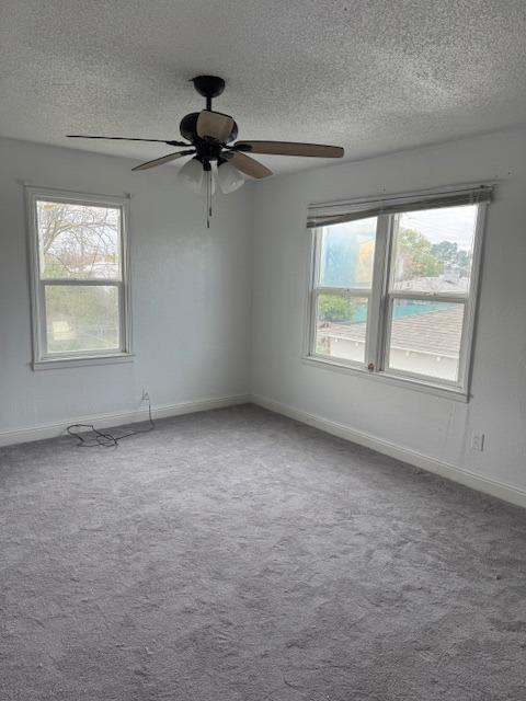 spare room with baseboards, carpet floors, a textured ceiling, and ceiling fan