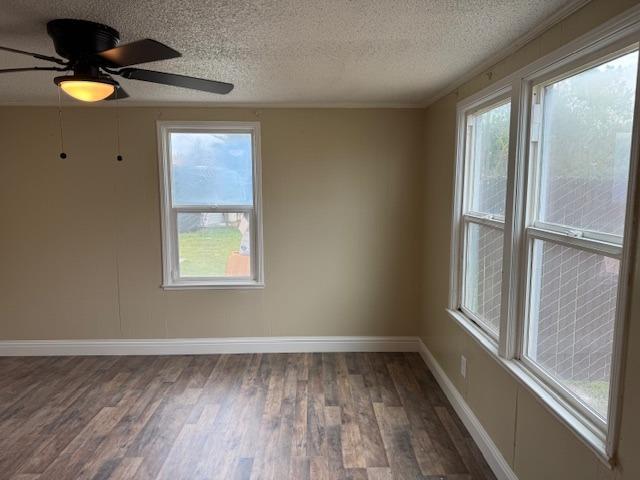 spare room with baseboards, a textured ceiling, wood finished floors, and a ceiling fan