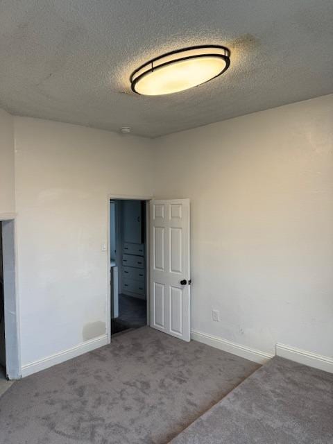 carpeted empty room with baseboards and a textured ceiling