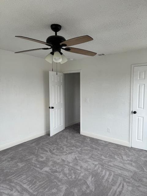 unfurnished room with a ceiling fan, visible vents, baseboards, carpet floors, and a textured ceiling