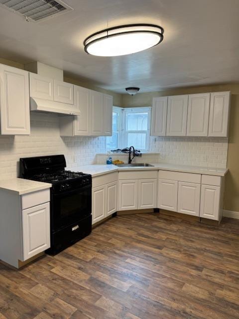 kitchen with dark wood finished floors, a sink, light countertops, under cabinet range hood, and black range with gas stovetop