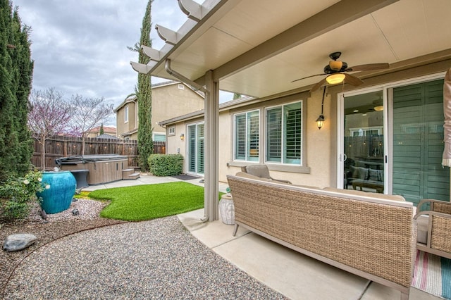 view of patio with a hot tub, a fenced backyard, and a ceiling fan