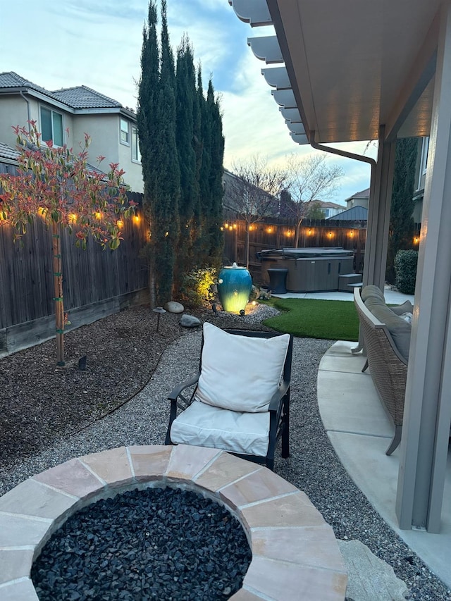 view of patio with an outdoor fire pit, a hot tub, and a fenced backyard