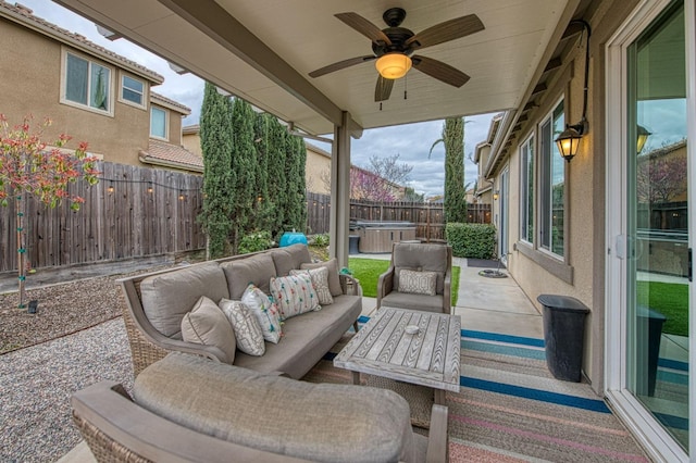 view of patio featuring an outdoor hangout area, a hot tub, a fenced backyard, and a ceiling fan