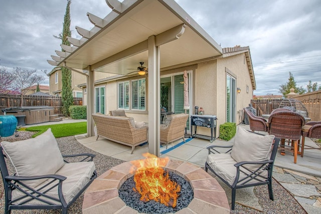 view of patio / terrace with an outdoor living space with a fire pit, a fenced backyard, and a hot tub