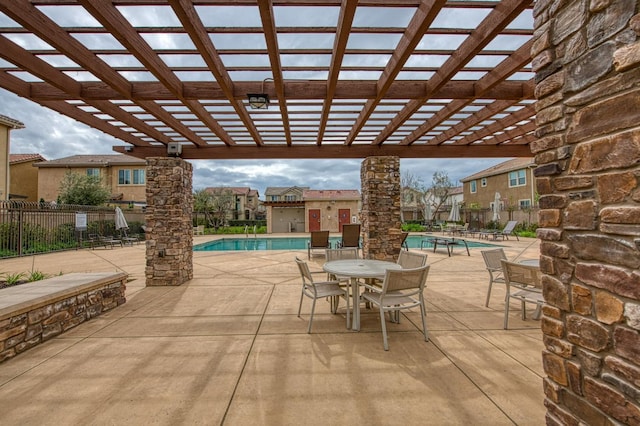 view of patio with a community pool, fence, and a pergola