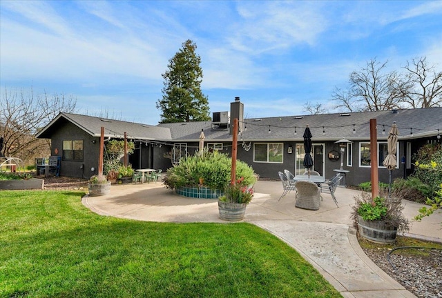 rear view of house with a yard, stucco siding, and a patio area