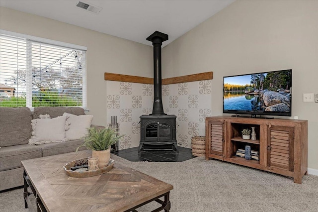 tiled living area featuring visible vents, carpet flooring, a wood stove, and vaulted ceiling