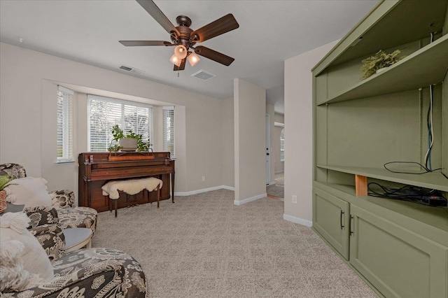 sitting room with visible vents, light colored carpet, baseboards, and a ceiling fan