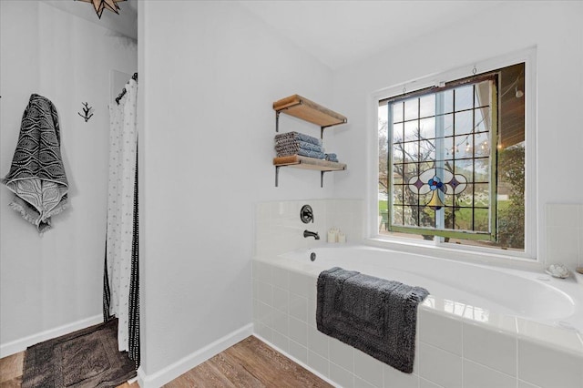 bathroom featuring a bath, wood finished floors, and baseboards