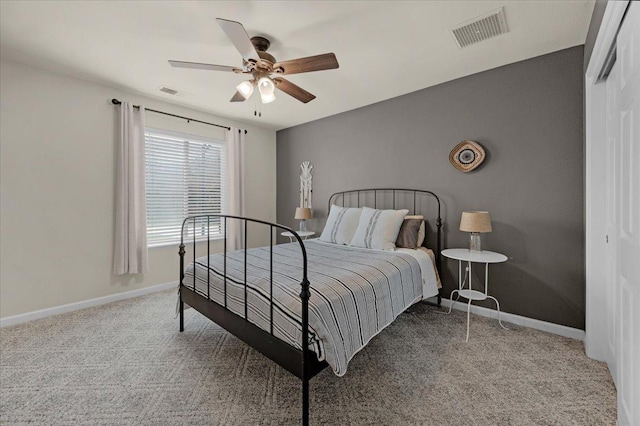 carpeted bedroom with visible vents, baseboards, a closet, and a ceiling fan