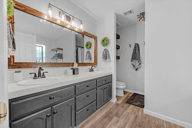 bathroom featuring a sink, visible vents, wood finished floors, and double vanity