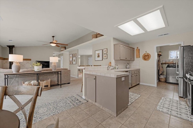 kitchen with light tile patterned flooring, visible vents, backsplash, and tile counters