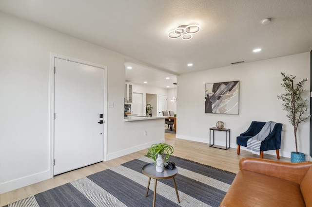 living area featuring recessed lighting, visible vents, baseboards, and light wood finished floors