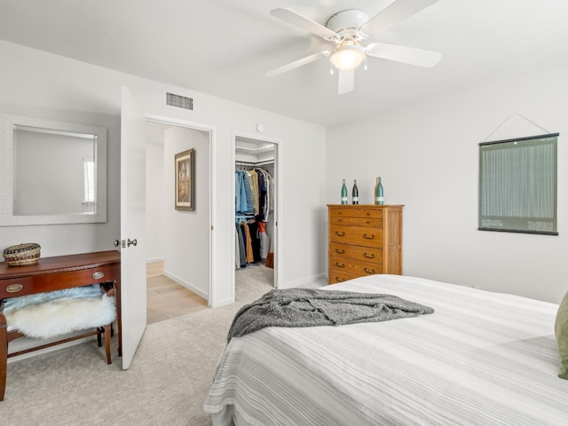 bedroom with a walk in closet, baseboards, carpet floors, a closet, and a ceiling fan