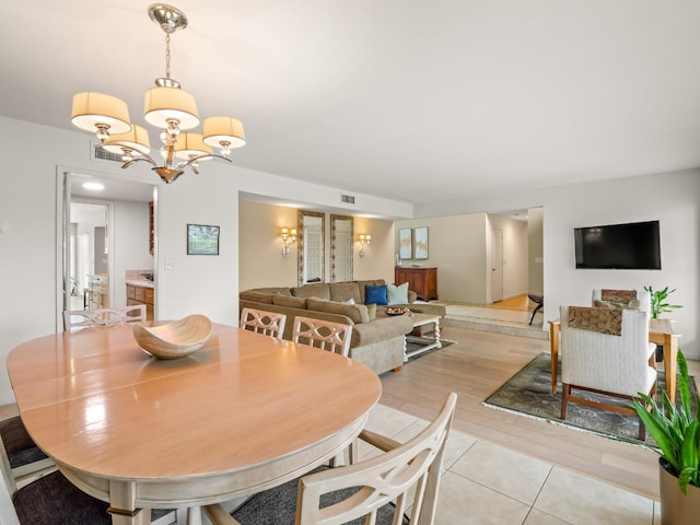 dining space with light tile patterned floors, visible vents, and a notable chandelier