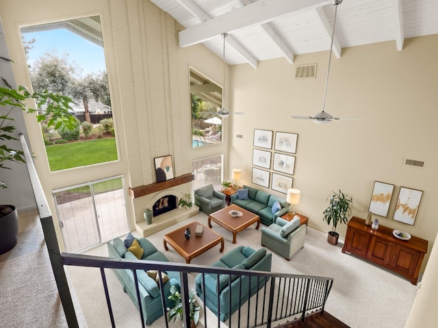 living room featuring carpet, visible vents, beam ceiling, a fireplace, and wood ceiling