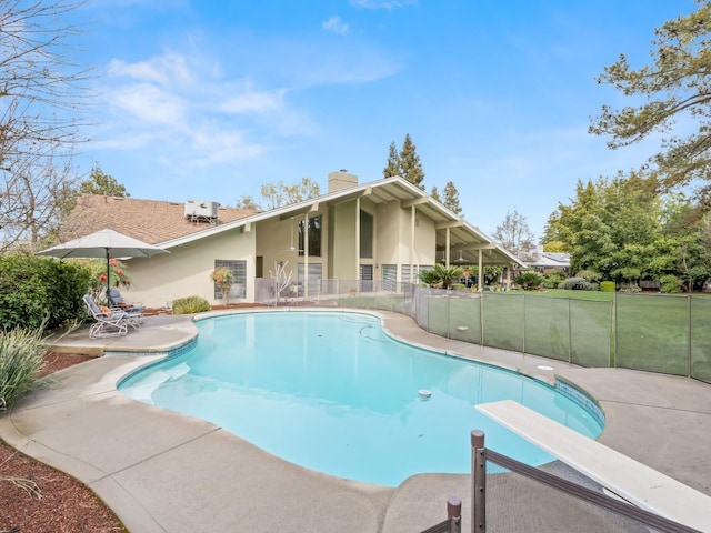 view of swimming pool featuring a patio area, a fenced in pool, a diving board, and fence