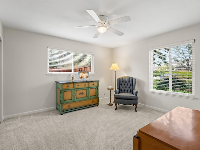 sitting room featuring baseboards, light colored carpet, and a ceiling fan