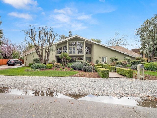 mid-century modern home featuring a front yard, a balcony, and driveway