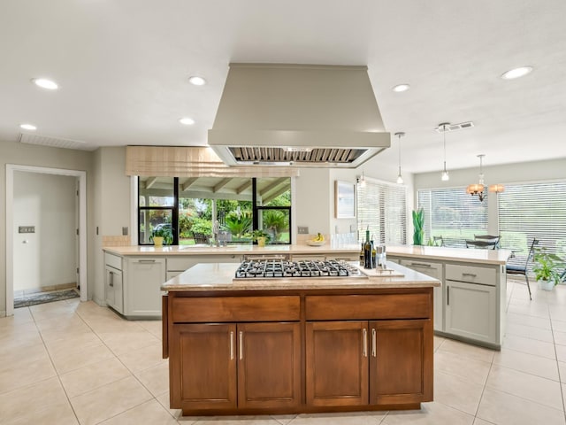 kitchen with visible vents, plenty of natural light, a kitchen island, and island range hood