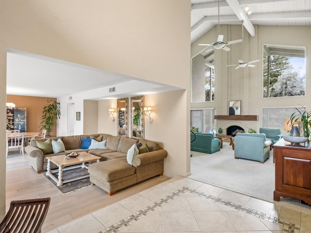 living room with visible vents, beamed ceiling, light tile patterned floors, a fireplace, and high vaulted ceiling