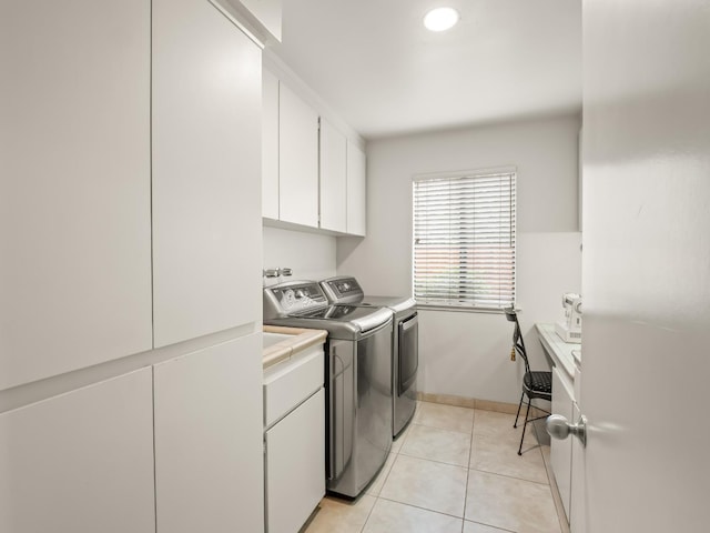 washroom featuring light tile patterned floors, cabinet space, baseboards, and washing machine and clothes dryer