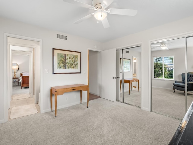 bedroom with visible vents, light colored carpet, two closets, and baseboards