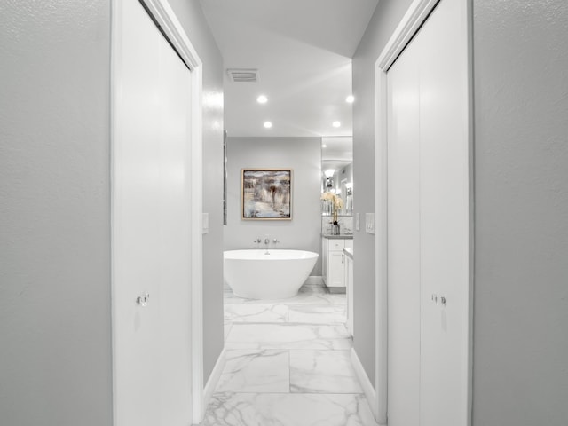 bathroom featuring visible vents, baseboards, a freestanding bath, marble finish floor, and vanity