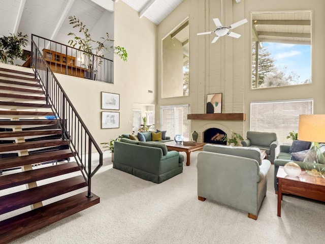 living area with stairway, high vaulted ceiling, ceiling fan, beamed ceiling, and carpet flooring